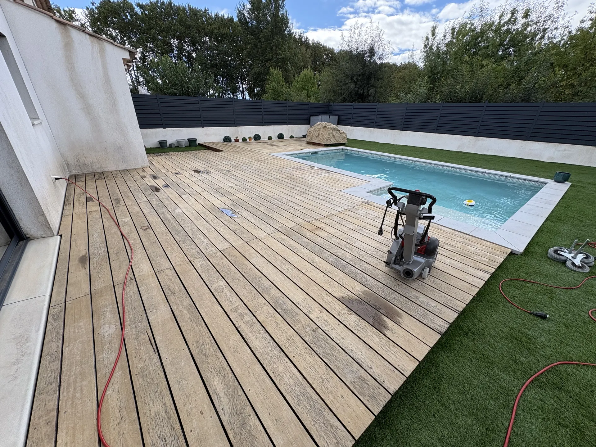 Terrasse en bois autour d'une piscine, bordée de gazon, avant rénovation