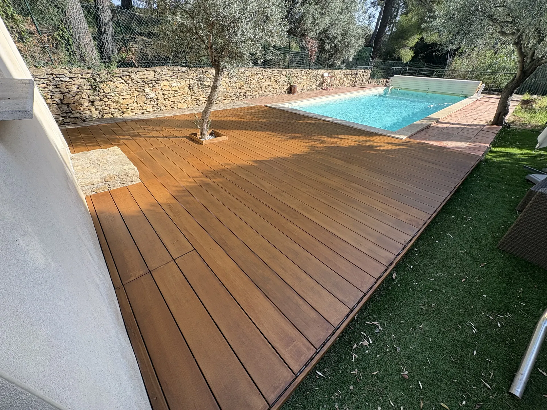 Plage de piscine en bois au pied d'un olivier, après rénovation