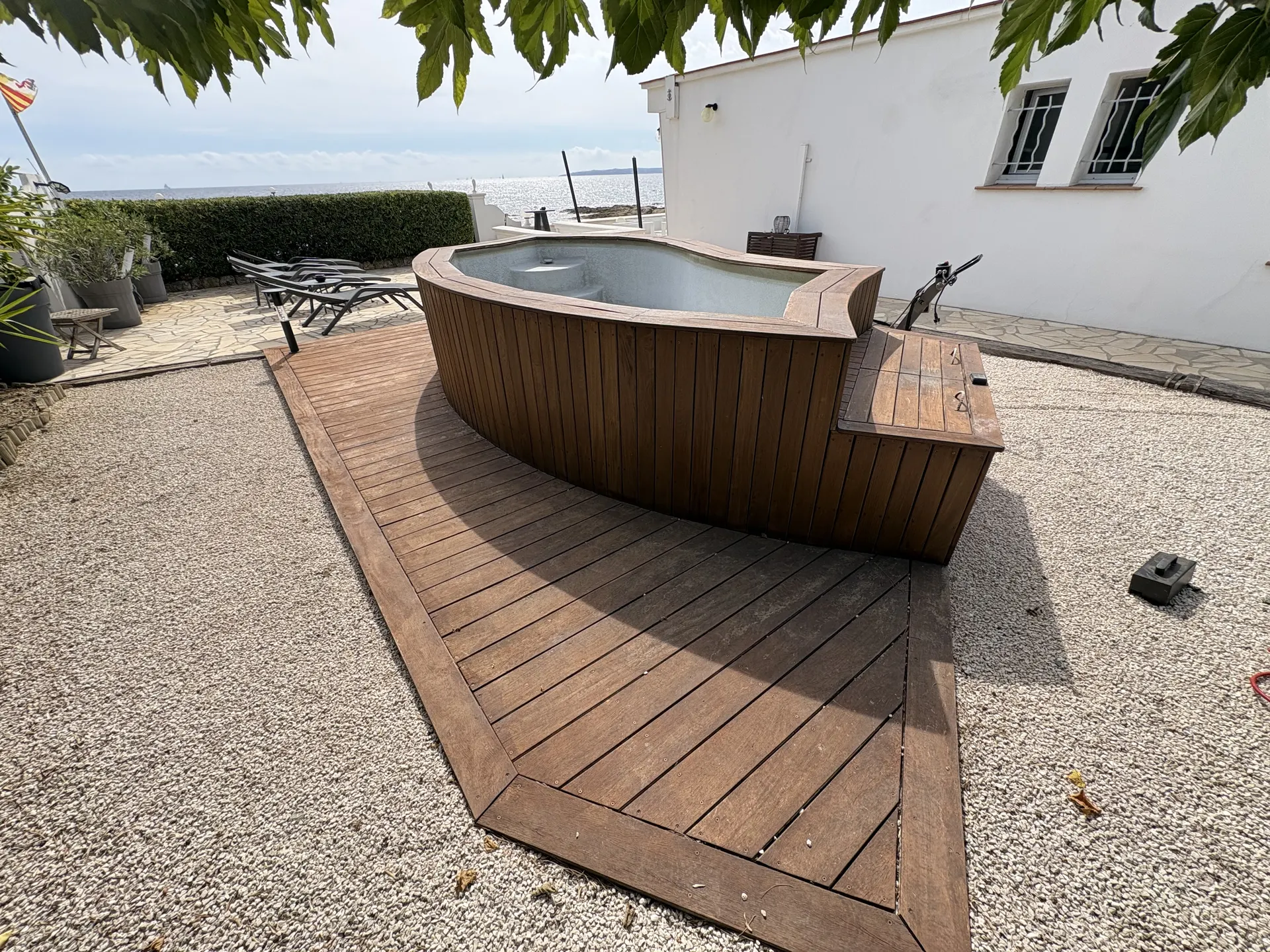 Deck en bois autour d'un spa, bordé de gravier