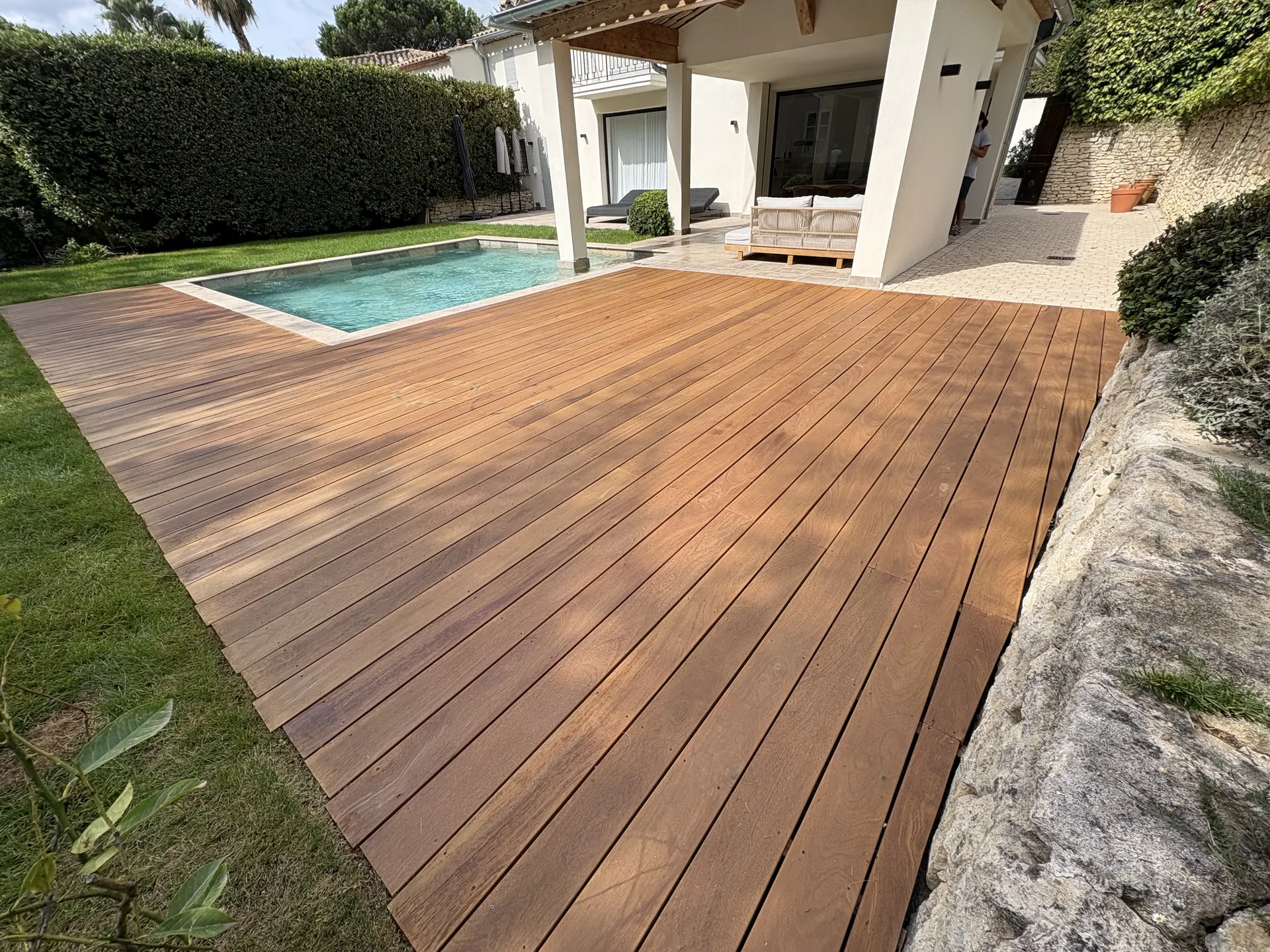 Terrasse en bois exotique autour de la piscine d'une villa, après rénovation