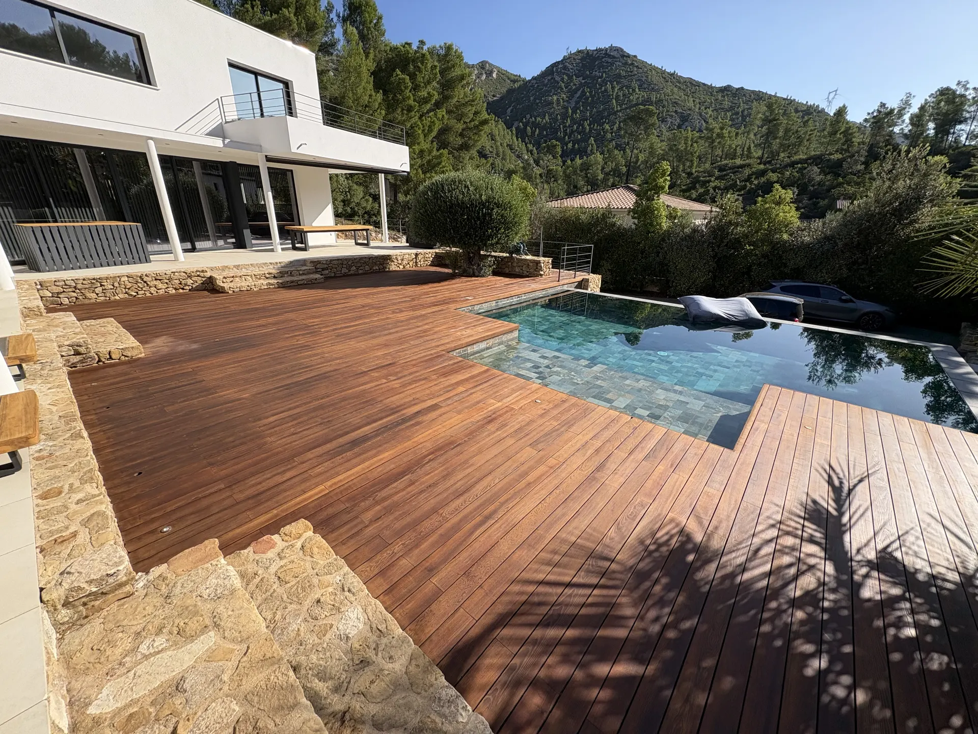 Plage de piscine à débordement face aux collines, après rénovation