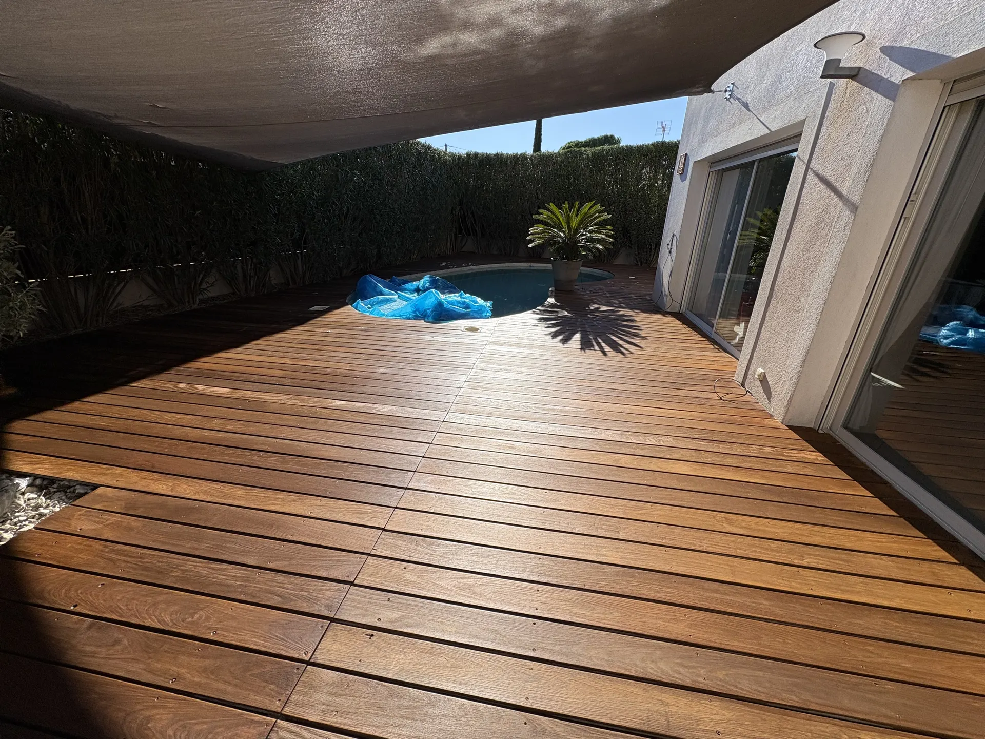 Terrasse en bois sous voile d'ombrage, après rénovation